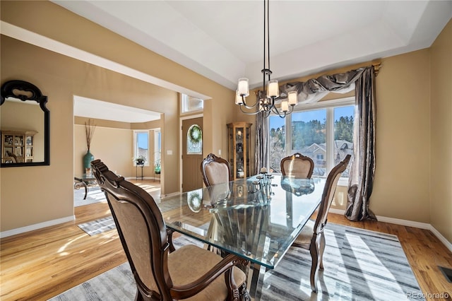 dining space featuring an inviting chandelier, light hardwood / wood-style floors, and a tray ceiling