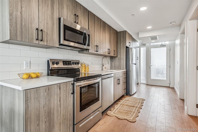 kitchen with light hardwood / wood-style floors, sink, stainless steel appliances, and tasteful backsplash