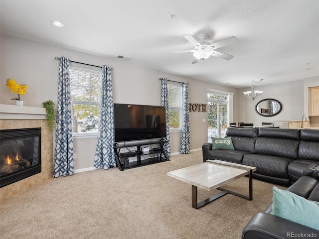 carpeted living room featuring a fireplace, ceiling fan with notable chandelier, and sink