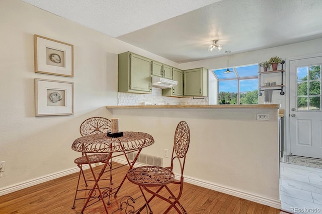 458 Rolling Hills Dr, Colorado Springs, CO 80919 - kitchen with green cabinets, under cabinet range hood, light wood-type flooring, tasteful backsplash, and open shelves
