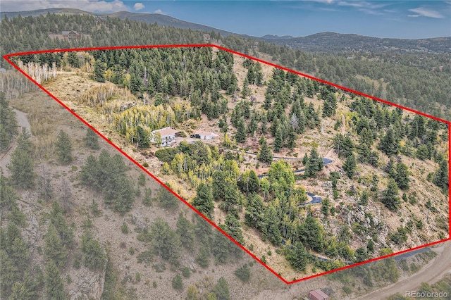 drone / aerial view featuring a wooded view and a mountain view