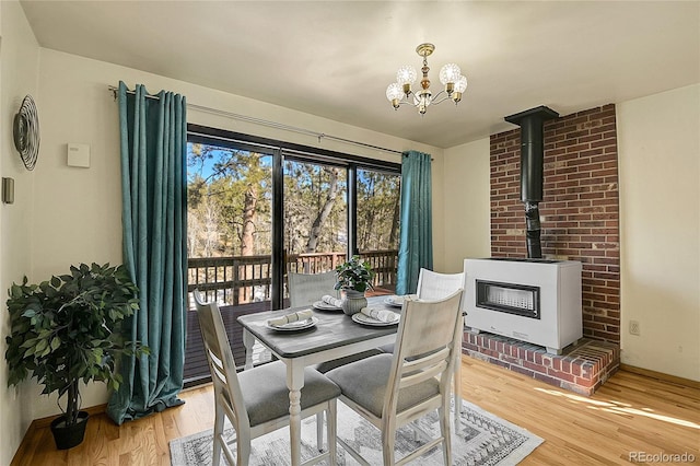 dining room featuring a wood stove, a notable chandelier, and light hardwood / wood-style flooring