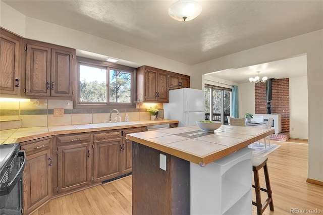 kitchen with sink, a wood stove, white refrigerator, stove, and tile counters