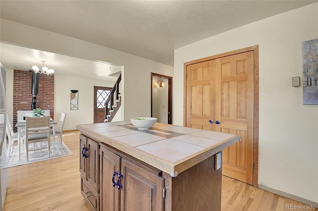 kitchen with hanging light fixtures, tile counters, a center island, and light wood-type flooring