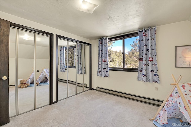 unfurnished bedroom with two closets, a baseboard radiator, light colored carpet, and a textured ceiling