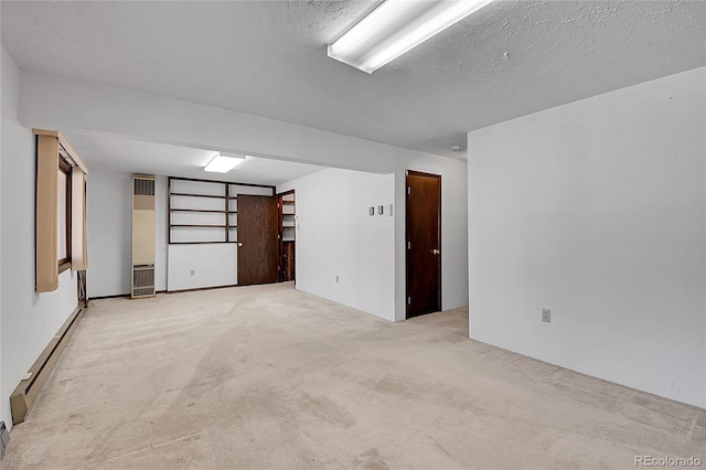 carpeted spare room with a textured ceiling and baseboard heating