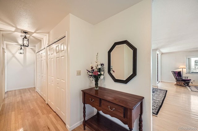 hall featuring light wood-type flooring and baseboards