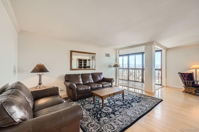 living room featuring visible vents, baseboards, expansive windows, ornamental molding, and wood finished floors