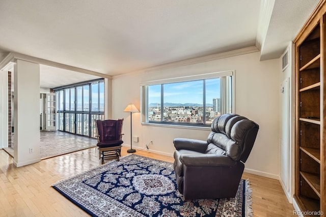 living area with wood finished floors, baseboards, visible vents, a city view, and crown molding