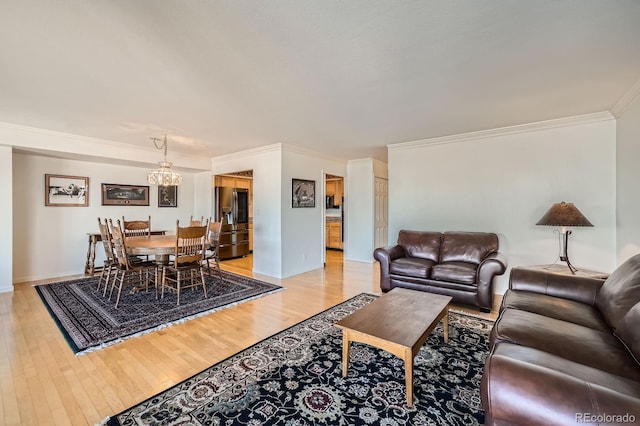 living room featuring baseboards, a notable chandelier, light wood-style flooring, and ornamental molding