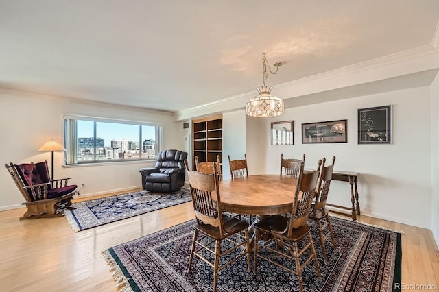 dining space featuring crown molding, wood finished floors, baseboards, and a chandelier