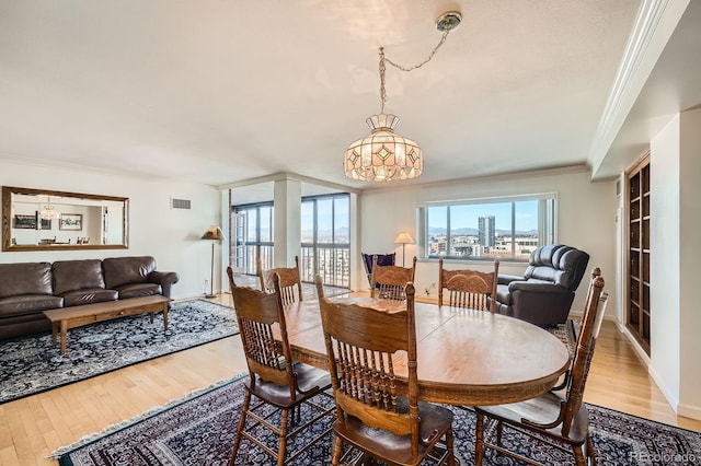 dining area featuring visible vents, baseboards, light wood-style flooring, and ornamental molding