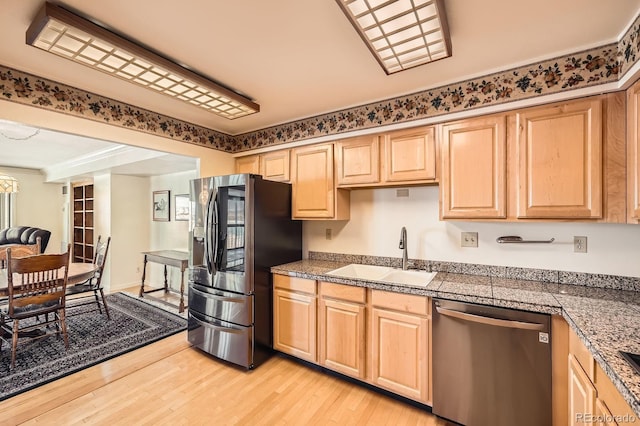 kitchen with tile counters, light brown cabinets, appliances with stainless steel finishes, and a sink