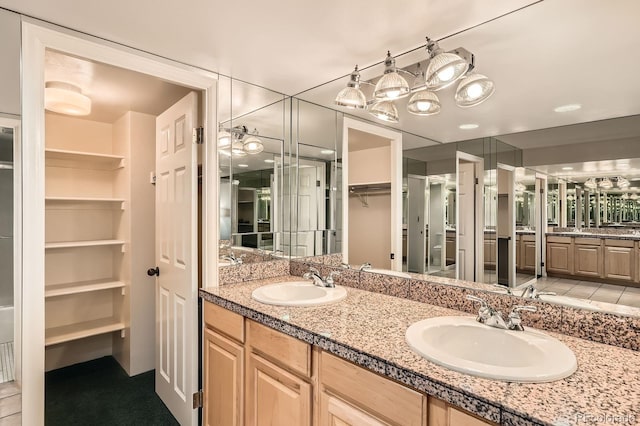 full bath featuring a sink, a walk in closet, and double vanity