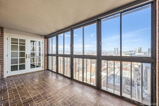 unfurnished sunroom featuring a wealth of natural light, french doors, and a view of city