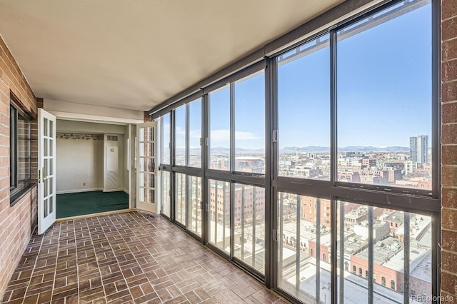 unfurnished sunroom with a wealth of natural light, french doors, and a view of city