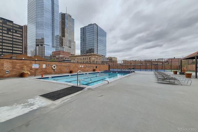 community pool featuring a view of city and fence