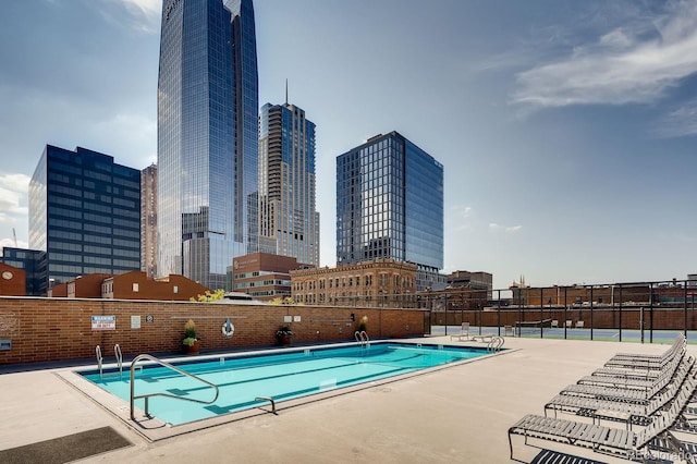 pool with a patio area, a view of city, and fence