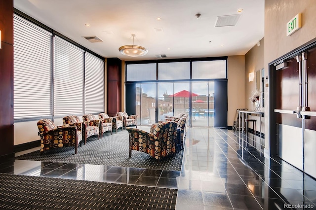 interior space with a wall of windows, granite finish floor, and visible vents