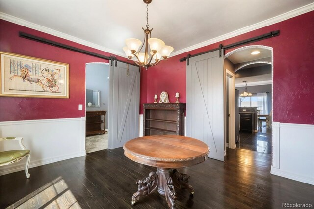 10525 Mt Sherman Way, Peyton, CO 80831 - dining room with a barn door, wainscoting, wood finished floors, crown molding, and a chandelier