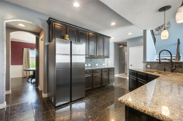 10525 Mt Sherman Way, Peyton, CO 80831 - kitchen featuring freestanding refrigerator, baseboards, a sink, dark brown cabinetry, and arched walkways