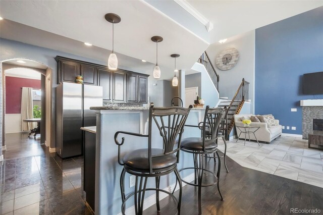 10525 Mt Sherman Way, Peyton, CO 80831 - kitchen featuring freestanding refrigerator, a kitchen breakfast bar, dark brown cabinetry, baseboards, and pendant lighting