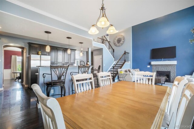 10525 Mt Sherman Way, Peyton, CO 80831 - dining area with arched walkways, a tiled fireplace, stairs, and baseboards