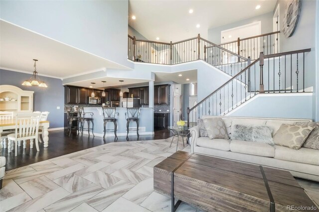 10525 Mt Sherman Way, Peyton, CO 80831 - living area featuring a chandelier, stairway, recessed lighting, a high ceiling, and ornamental molding