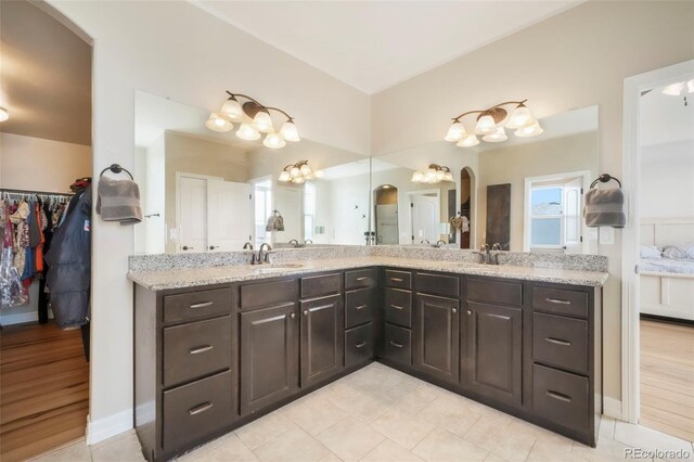 10525 Mt Sherman Way, Peyton, CO 80831 - bathroom featuring double vanity, baseboards, tile patterned floors, and a chandelier