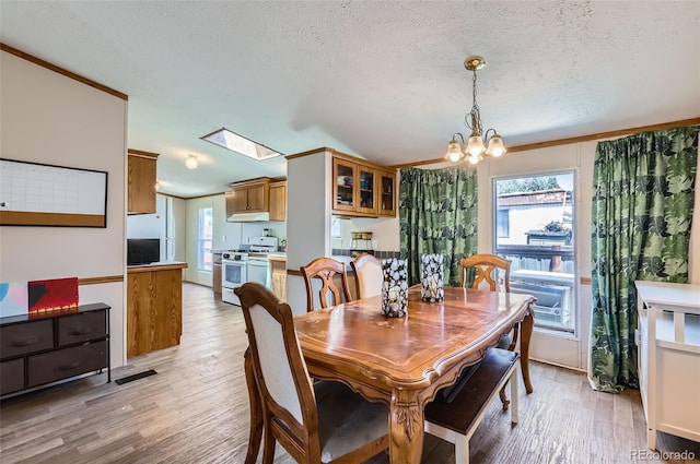 3715 Mcavoy Ave, Evans, CO 80620 - dining room featuring light wood-style flooring, vaulted ceiling, a chandelier, plenty of natural light, and a textured ceiling