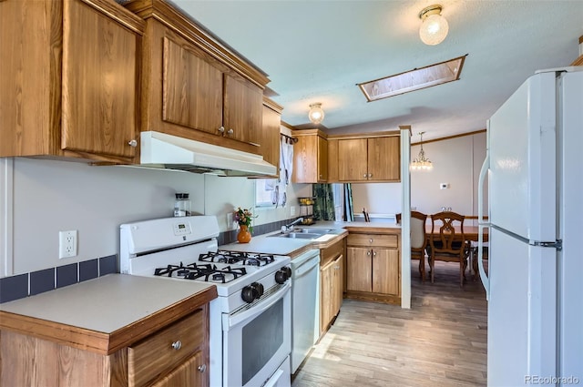 3715 Mcavoy Ave, Evans, CO 80620 - kitchen with white appliances, under cabinet range hood, light wood-style flooring, a skylight, and brown cabinets