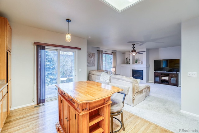3779 Aspen Hollow Ct, Castle Rock, CO 80104 - kitchen featuring a tile fireplace, a ceiling fan, baseboards, hanging light fixtures, and light wood finished floors