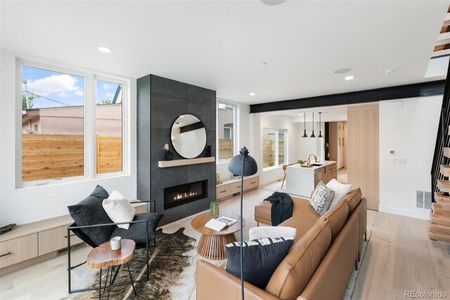 living room featuring light wood-type flooring, a fireplace, and sink