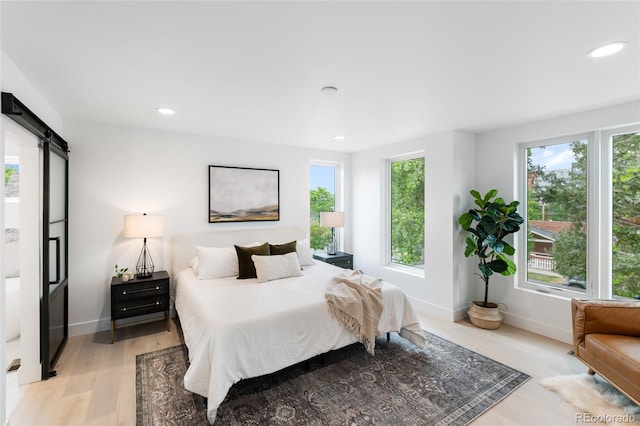 bedroom featuring light wood-type flooring and a barn door