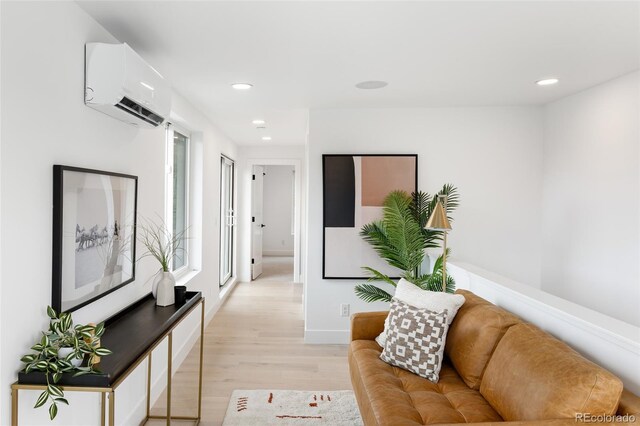 living room featuring an AC wall unit and light wood-type flooring