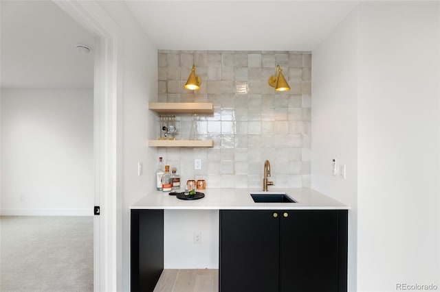 bar with light carpet, tasteful backsplash, baseboards, wet bar, and a sink