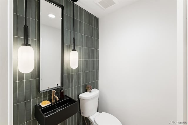 bathroom featuring tile walls, sink, and toilet