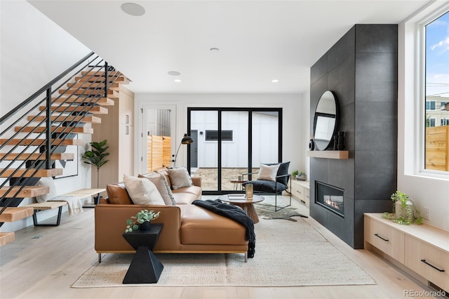 living area with a large fireplace, light wood finished floors, stairs, and recessed lighting