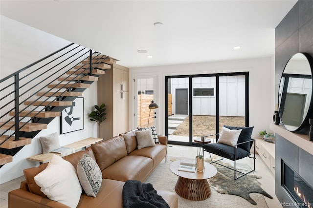 living room featuring stairs, a glass covered fireplace, and recessed lighting