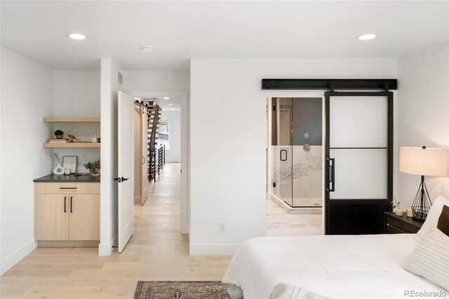 bedroom with light hardwood / wood-style flooring and a barn door