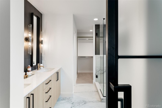 bathroom featuring marble finish floor, double vanity, recessed lighting, a spacious closet, and a sink