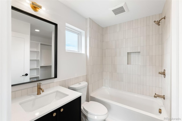 full bathroom featuring vanity, tiled shower / bath combo, and toilet