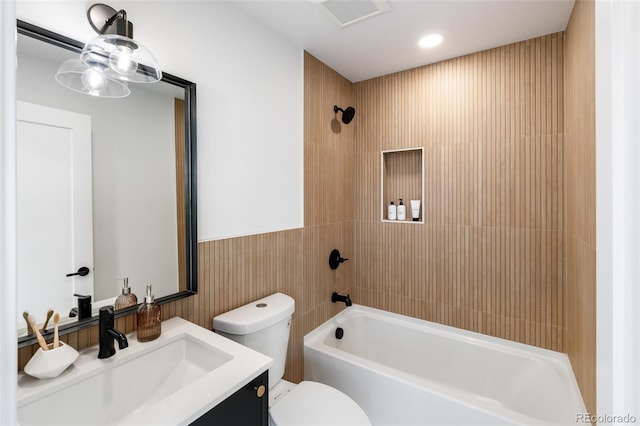 bathroom with shower / bath combination, visible vents, toilet, a wainscoted wall, and vanity