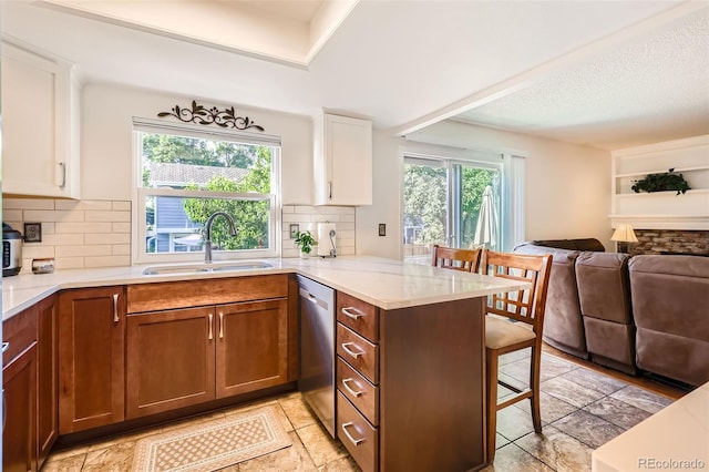 8156 Carr Cir, Arvada, CO 80005 - kitchen with stainless steel dishwasher, open floor plan, a kitchen bar, a peninsula, and tasteful backsplash