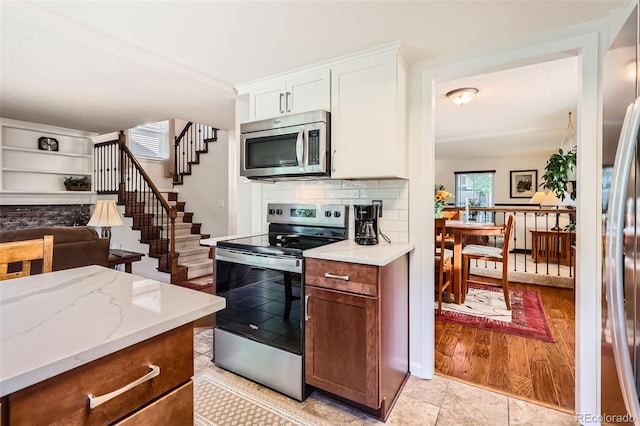 8156 Carr Cir, Arvada, CO 80005 - kitchen with appliances with stainless steel finishes, white cabinetry, light stone counters, open floor plan, and backsplash