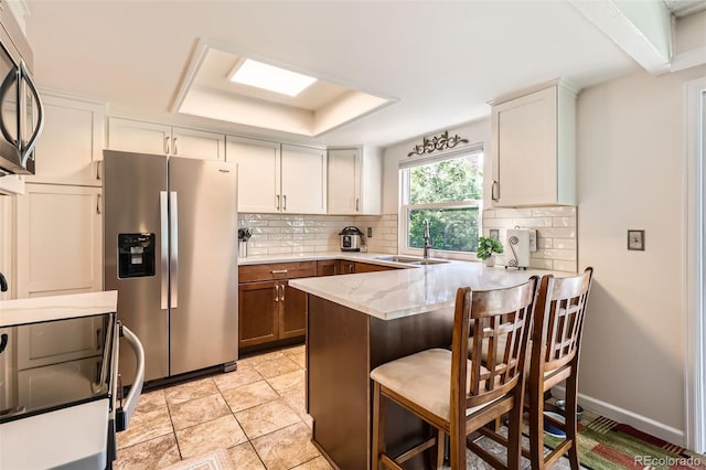 8156 Carr Cir, Arvada, CO 80005 - kitchen with appliances with stainless steel finishes, a peninsula, decorative backsplash, and light stone countertops