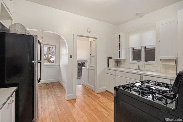 3159 36th Ave, Denver, CO 80211 - kitchen with white cabinets, freestanding refrigerator, gas stove, and a sink