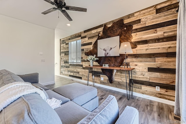 living area with ceiling fan, wood walls, wood finished floors, baseboards, and recessed lighting