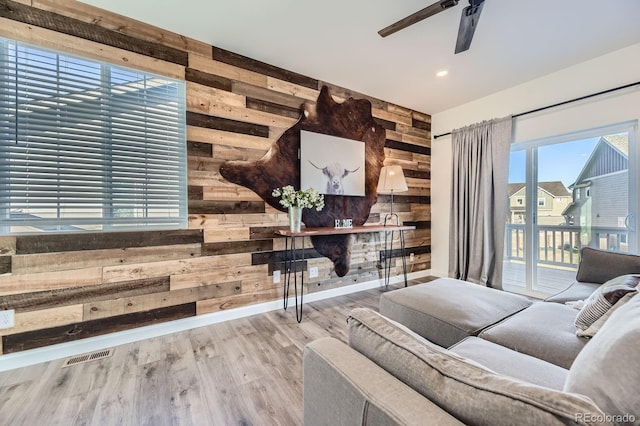 living room with a ceiling fan, visible vents, wood walls, wood finished floors, and recessed lighting