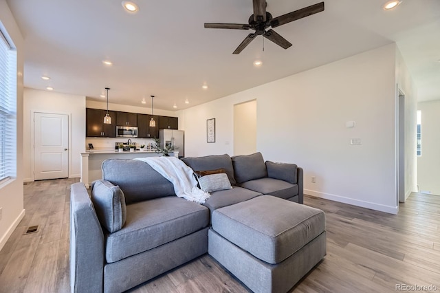 living area featuring visible vents, baseboards, recessed lighting, a ceiling fan, and light wood finished floors